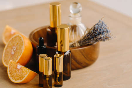 Essential oil in bottles with the aroma of orange and lavender lying on a wooden surface.の写真素材