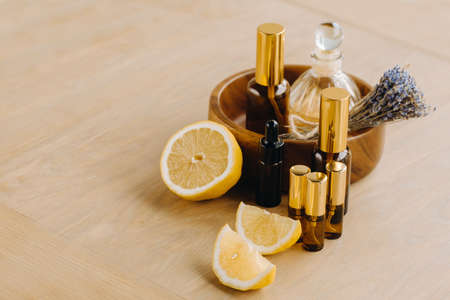 Essential oil in bottles with lemon and lavender fragrance, lying on a wooden surface.の写真素材