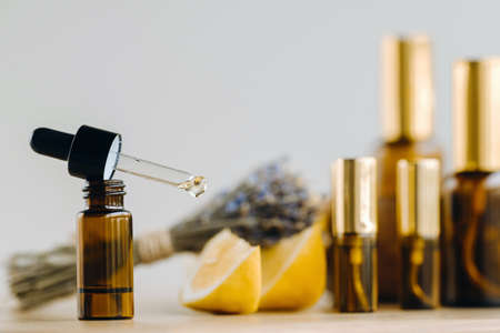 Essential oil in bottles with lemon and lavender fragrance, lying on a wooden surface.の写真素材