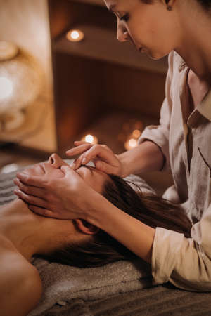 A cosmetologist girl does a facial and neck massage to a girl in the office for skin elasticity.の写真素材