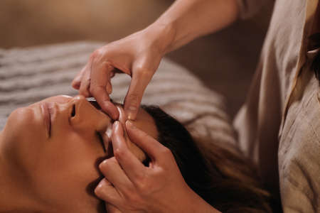 A cosmetologist girl does a facial and neck massage to a girl in the office for skin elasticity.