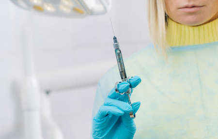 close-up of a dentists hand holding an injection syringe for a patient in the officeの写真素材