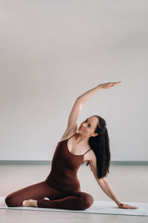 a woman in a brown suit does yoga in a fitness room . Healthy lifestyle, fitness, training, self-care.の写真素材