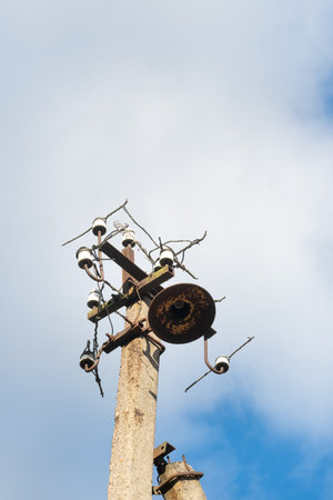 One old concrete street pole with a rusty iron part at the top and cut wires, Installation or dismantling of the power grid. A broken energy pillar.の写真素材