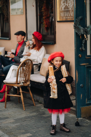 A stylish girl with baguettes stands near the store against the background of her parents.の写真素材
