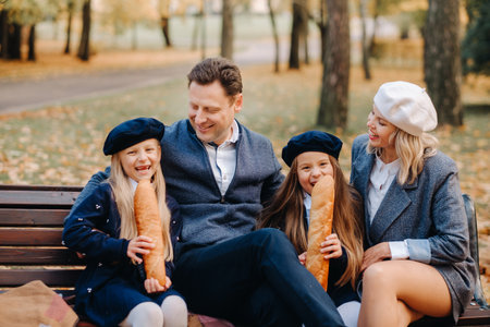 A large family is sitting on a bench in an autumn park. Happy people in the autumn parkの写真素材