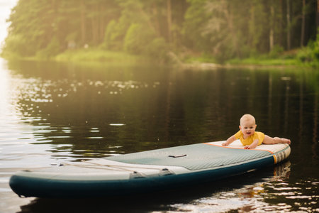 The child lies floating on the water on a large sup board. Water sports