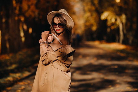 Sexy girl in a coat and hat in an autumn sunny parkの写真素材