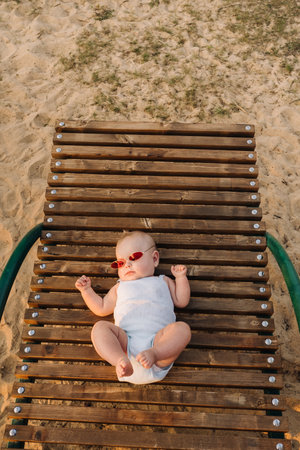 Top view of a happy little boy with glasses lying on a wooden sunbedの写真素材