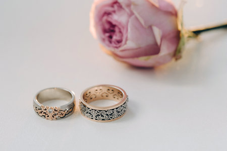 Designer wedding rings lying on the surface with a rose. Two wedding rings.