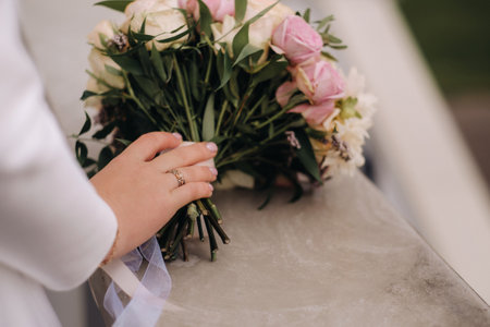 The bride's hand is on the wedding bouquet of fresh pink flowers. wedding details.の写真素材