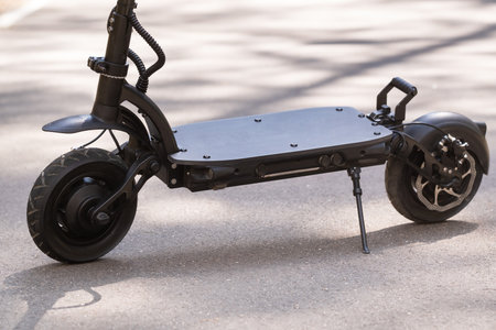 Black Electric scooter standing on the running board on the street.