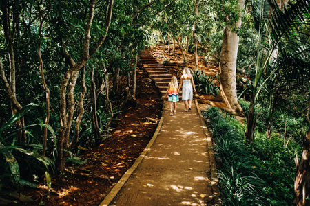 A young woman and a little girl walk along a path along the exotic trees of the Chamarelle National Park on the island of Mauritiusの写真素材