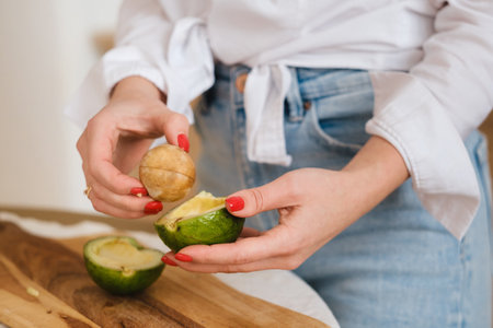 Close-up of a girl's hand holding an avocado cut in two.の写真素材