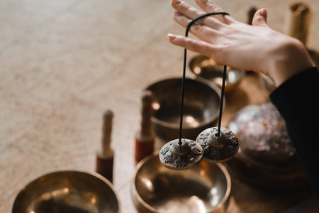 Close-up of a womans hand holding Tibetan bells for sound therapy. Tibetan cymbalsの写真素材