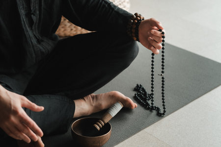 close-up of a man in a black kimono sitting in a lotus position on a gym mat in the interior.