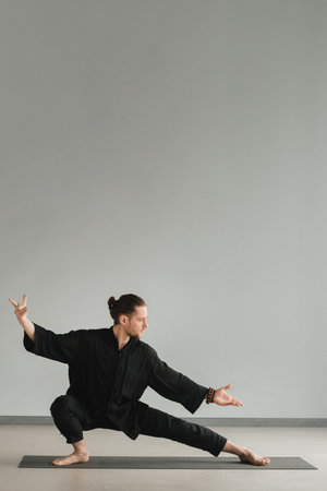 A man in black kimano practicing qigong energy exercises indoors.の写真素材