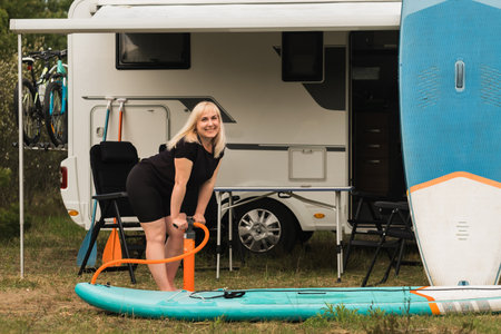 A woman inflates a sup-board for swimming near her motorhome.の写真素材