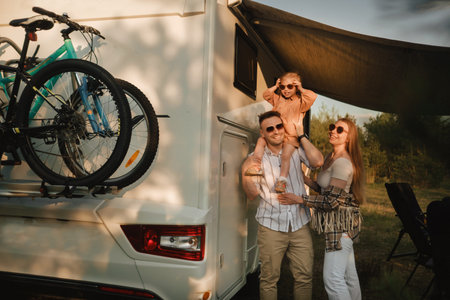 a young family with glasses is standing next to their mobile home. Dad, mom and daughter together near the motorhome.の写真素材
