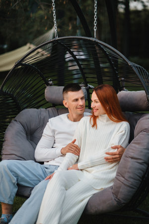 A happy family is sitting in a hammock on the lawn near the house.の写真素材
