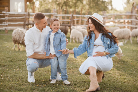 Stylish family in summer on a village farm with sheep.の写真素材
