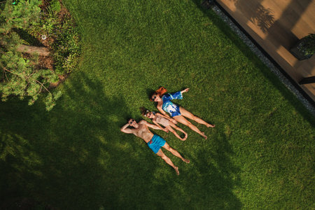 Top view of a happy family in swimsuits lying on the green grass.の写真素材