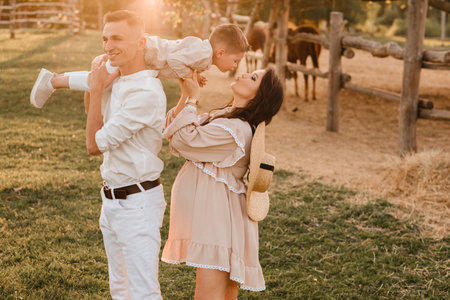 A stylish family in the countryside at sunset. A pregnant woman with her husband and son in natureの写真素材