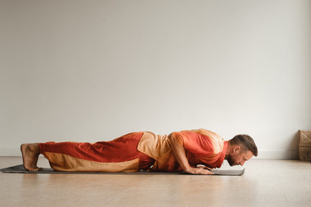 a man in an orange suit does yoga in a fitness room. The concept of health.