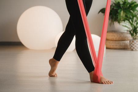 Close-up of the legs of a Girl in black doing fitness with red ribbons indoors.の写真素材