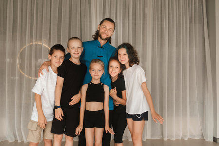 A joint portrait of a yoga coach and children standing in a fitness room.の写真素材
