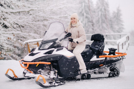 A cheerful woman rides a snowmobile in a winter forest.の写真素材