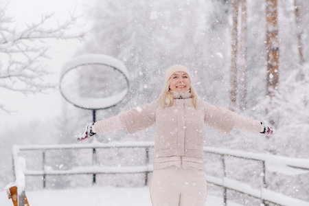 A cheerful woman stands under the snow in a winter forest.の写真素材