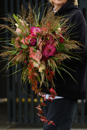 A large bouquet of mixed flowers in the hands of a woman. The work of a florist in a flower shop.の写真素材