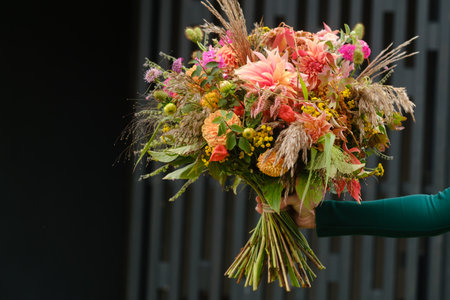 A large bouquet of mixed flowers in the hands of a woman. The work of a florist in a flower shop.の写真素材