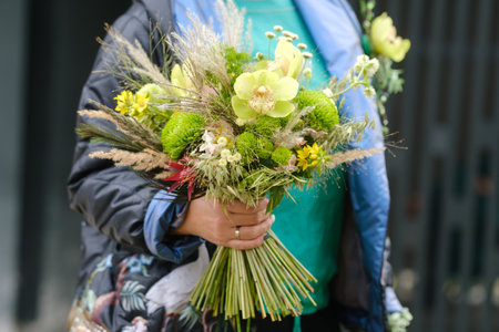 A large bouquet of mixed flowers in the hands of a woman. The work of a florist in a flower shop.の写真素材