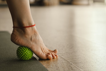 Close - up of the legs of a woman performing gymnastic exercises to correct flat feet during ball massage at home.の写真素材