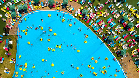 Top view of people relaxing in the pool on yellow inflatable circles and sun beds on the beach.の写真素材