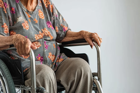 An elderly retired woman is sitting at home in a wheelchair.の素材