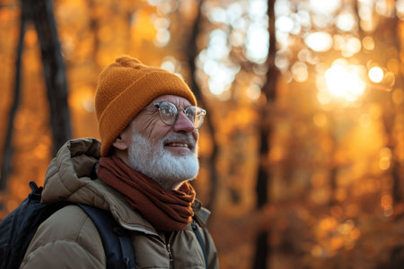 An elderly man is a traveler with a backpack in the autumn in the forest.の素材