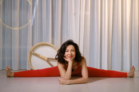 Woman in red tracksuit sitting on a twine with a drum in a gym.の写真素材