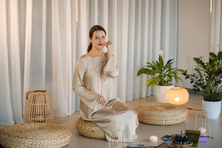 Beautiful Girl in beige dress and beads sitting indoors.の写真素材