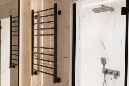 Modern black radiator on white marble wall in bathroom. New bathroom with granite white tiles.の写真素材