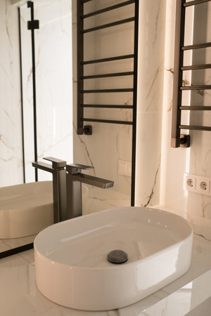Chrome water faucet and white pedestal sink in bathroom . Stylish bathroom.の写真素材