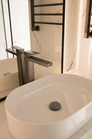 Chrome water faucet and white pedestal sink in bathroom . Stylish bathroom.の写真素材