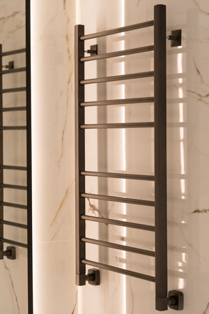 Modern black radiator on white marble wall in bathroom. New bathroom with granite white tiles.の写真素材