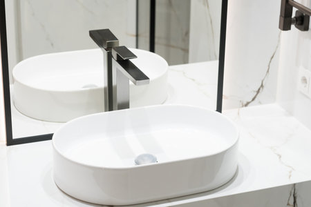 Stylish deluxe water faucet and white countertop sink in bathroom. Stylish bathroomの写真素材