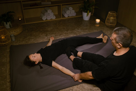Professional masseur gives Girl Thai massage in massage parlor. Traditional Asian stretching therapy.の写真素材