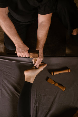 A man gives a relaxing Thai foot massage with a Tok-Sen massage kit at a beauty spa. Body care.の写真素材