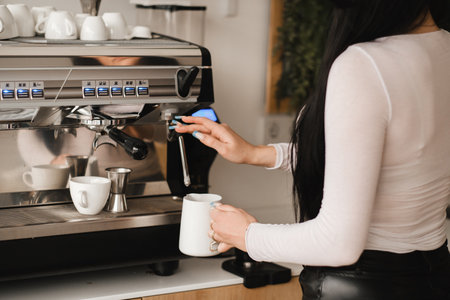 Girl making coffee on a large coffee machine with mugs in a cafe. The concept of making coffee in a coffee shop.の写真素材