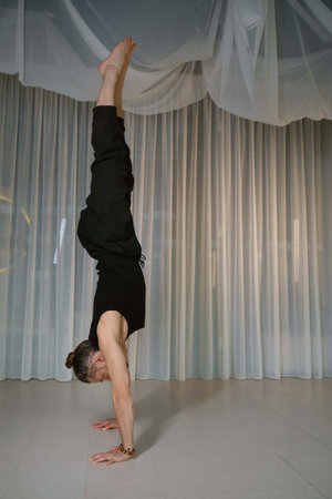 A man stands upside down on his hands in the gymの写真素材